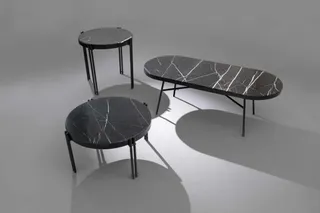 Three dark tables with white veined surfaces and slender metal legs.