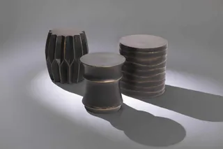 Three sculptural dark stools and side tables.