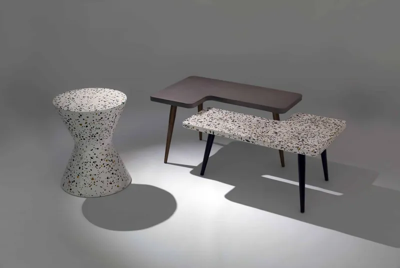 Set of tables and a terrazzo-style stool in a studio setting.