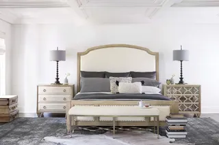 Upholstered bed, bedside cabinets, bench, lamps and dresser in a styled bedroom