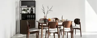 Wooden dining table and chairs with a dark shelving unit