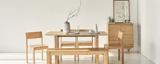 Wooden dining table, bench, chair and sideboard in a bright room