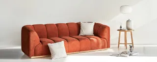 Rust-colored upholstered sofa with a small wooden side table