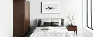 Bedroom with upholstered bed, dark wardrobe and wooden bedside table