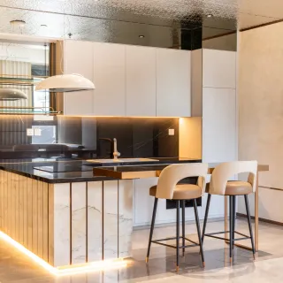 Contemporary kitchen with black stone island, white cabinetry and two bar stools