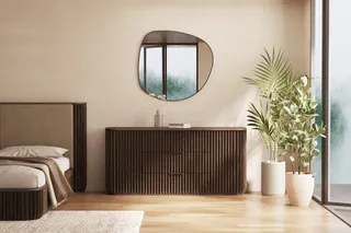 Dark fluted sideboard beside a bed in a modern bedroom