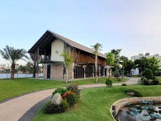 Modern timber-clad building beside landscaped lawns, paths and a pond.