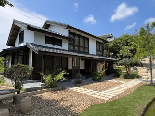 Japanese-style house with tiled roofs, landscaped garden and stone pathway.