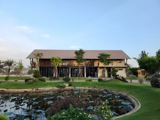 Long timber-accented building overlooking a landscaped lotus pond and lawn.