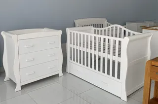 White baby crib and matching three-drawer dresser in a showroom