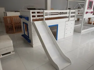 White children's bunk bed with slide and storage drawers in a showroom