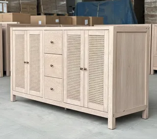 Wooden sideboard with cane-front doors and drawers in a warehouse