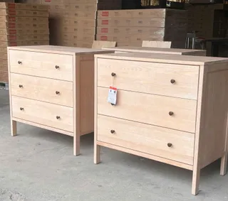 Two unfinished wooden chests of drawers in a warehouse