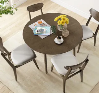 Round wooden dining table with four upholstered chairs in a bright interior.