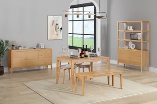 Wooden dining table, chairs, bench, sideboard and shelving in a staged room.