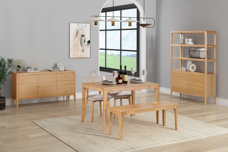 Wooden dining table, chairs, bench, sideboard and shelving in a staged room.