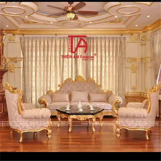 Ornate cream and gold living room with carved sofa, armchairs and glass coffee table