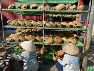 Workers handling woven rattan baskets and trays on outdoor shelving