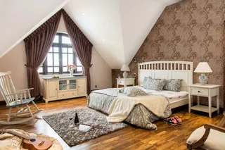 Bedroom with white bed, nightstands, rocking chair and cabinet