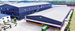 Aerial view of large factory buildings with loading docks and surrounding grounds