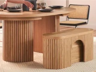Rounded wooden dining table and matching fluted bench in a dining room