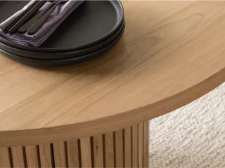 Close-up of a rounded wooden tabletop with fluted cylindrical base