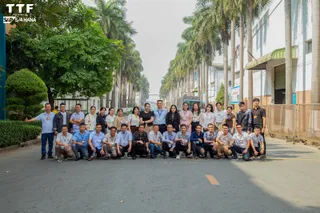 Employees posing outside a facility lined with palm trees