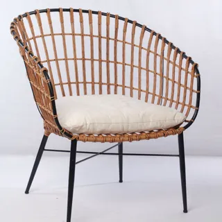Woven rattan lounge chair with a cream cushion and black metal legs