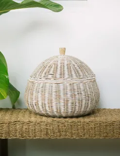 White woven lidded basket displayed on a textured woven table