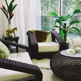 Living room arrangement with woven armchairs, ottoman, coffee table and plants