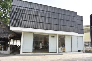 Exterior of a Vietnamese furniture building with a glass-fronted entrance and dark slatted facade.
