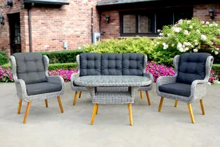 Gray woven loveseat and two armchairs with cushions in a garden setting