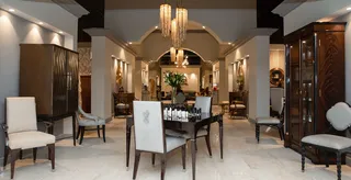 Furnished showroom displaying dining furniture, cabinets and upholstered chairs.