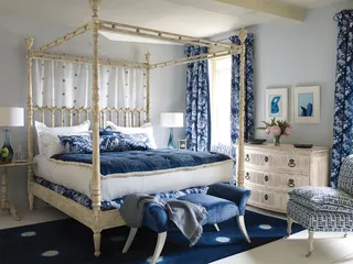 Ornate four-poster bed with blue-and-white bedding and matching furnishings.