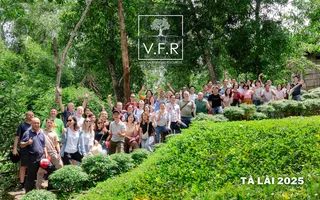 Large group of employees posing together in a green garden.