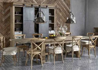 Dining room with a reclaimed-wood table, upholstered chairs, pendant lights and shelving.