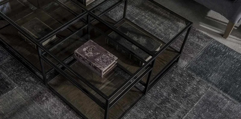 Black metal and glass coffee tables arranged on a textured rug.