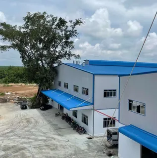 White industrial furniture factory with blue roofs, loading area and parked motorcycles