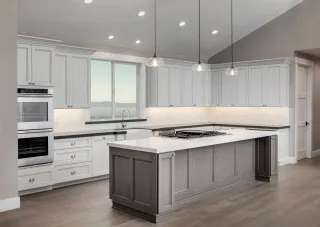 White fitted kitchen with a gray island, built-in appliances and pendant lights