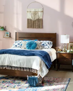 Dark wooden bed styled with blue and white bedding in a bedroom